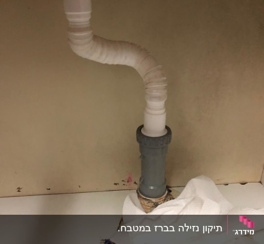 צינור פלסטיק מתחת לכיור עם ניירות